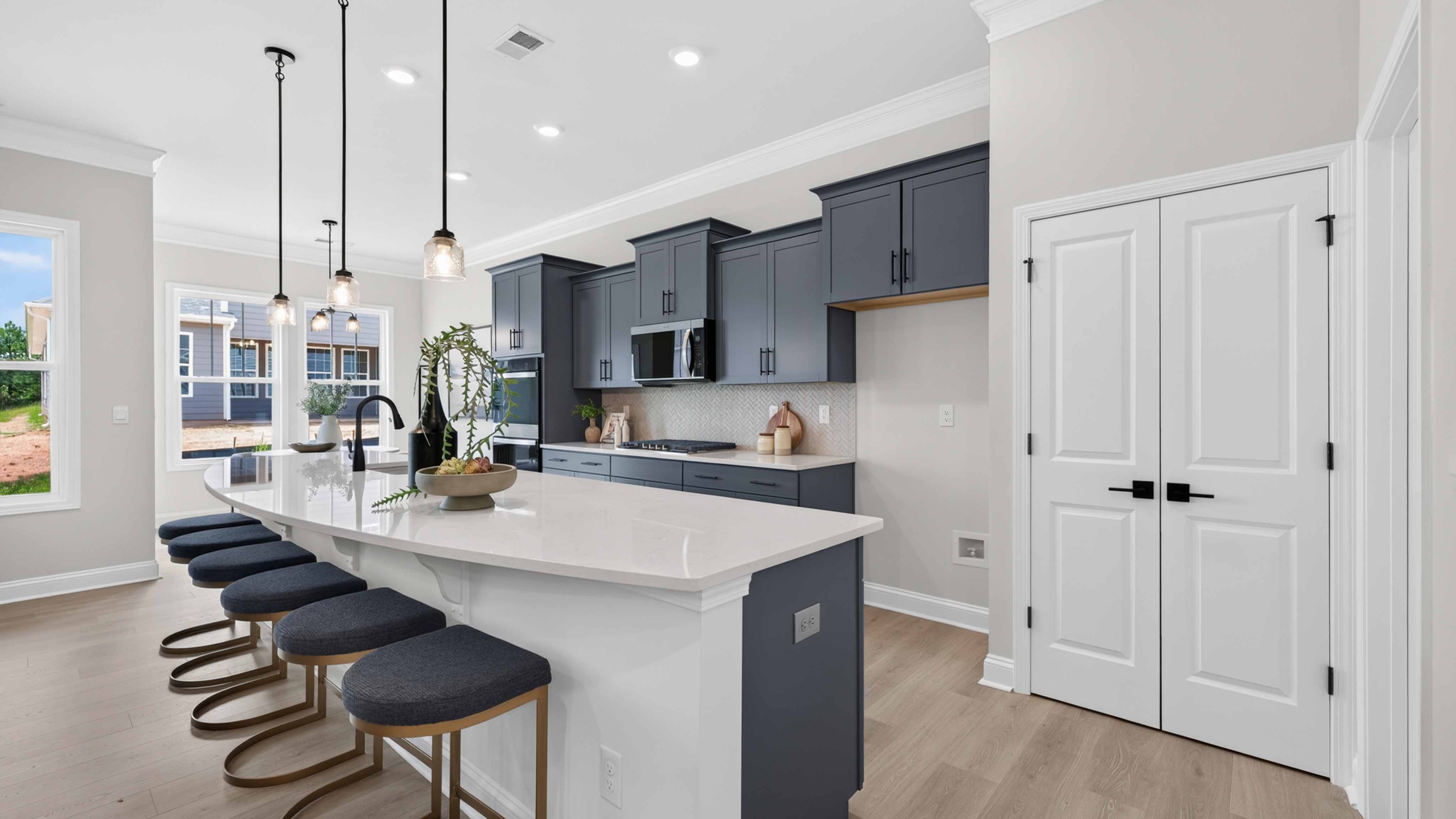Kitchen and island with wood floors, white cabinets and counters, stainless steel appliances, and seating at island bar