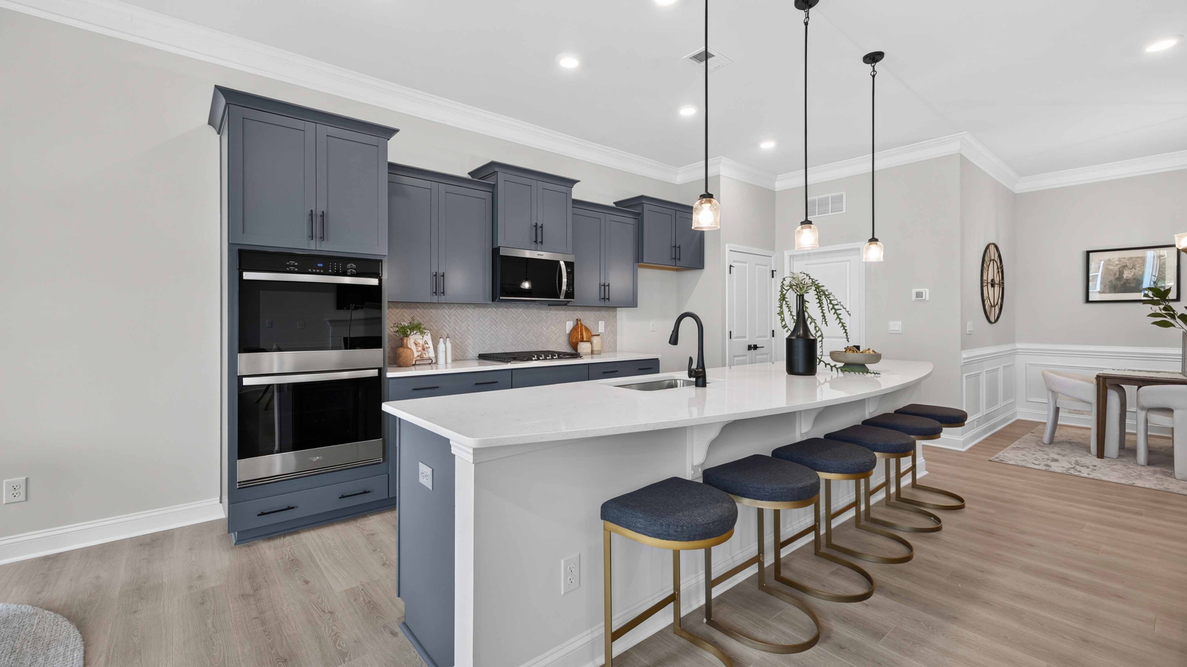 Kitchen and island with wood floors, white cabinets and counters, stainless steel appliances, and seating at island bar