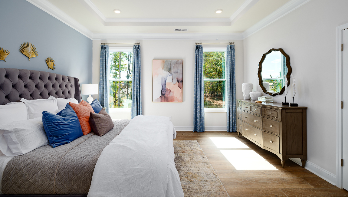 Primary bedroom with wood floors, and two large windows