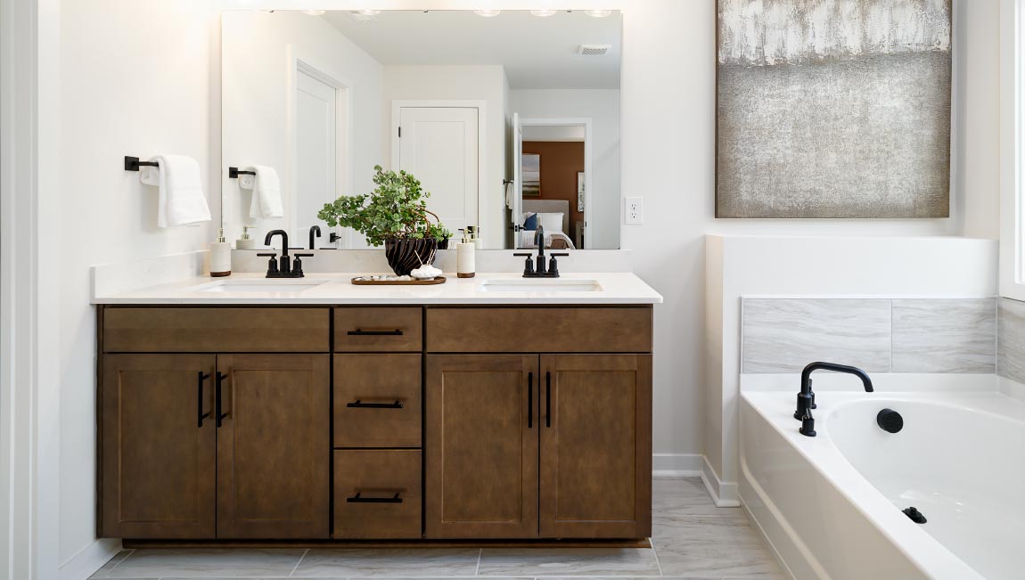 Primary bathroom with white cabinets, bathtub, and glass door shower