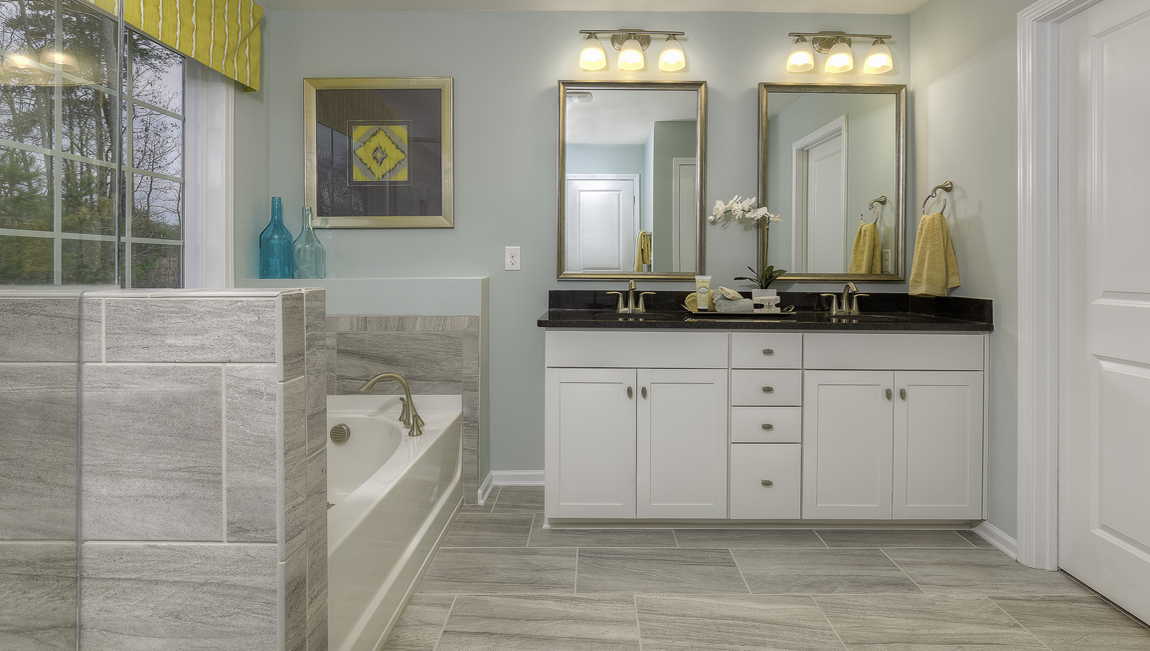 Primary bathroom with white cabinets, bathtub, and glass door shower
