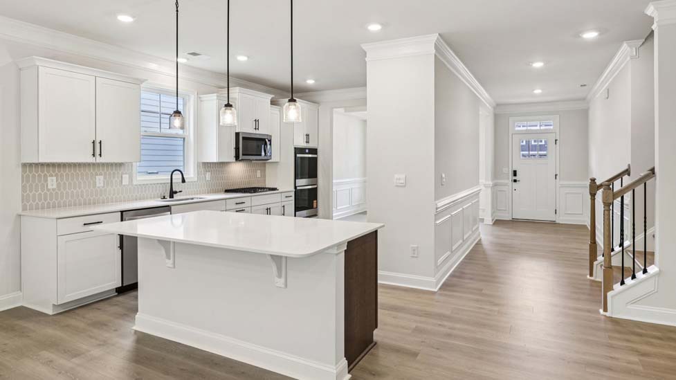 Kitchen and island with white cabinets, breakfast area at island bar, and stainless steel appliances