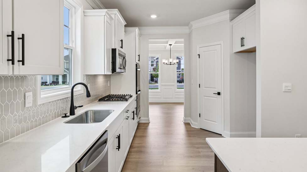 Kitchen and island with white cabinets, breakfast area at island bar, and stainless steel appliances