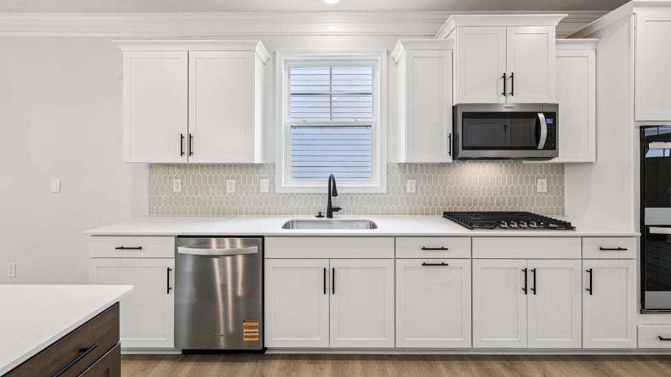 Kitchen and island with white cabinets, breakfast area at island bar, and stainless steel appliances