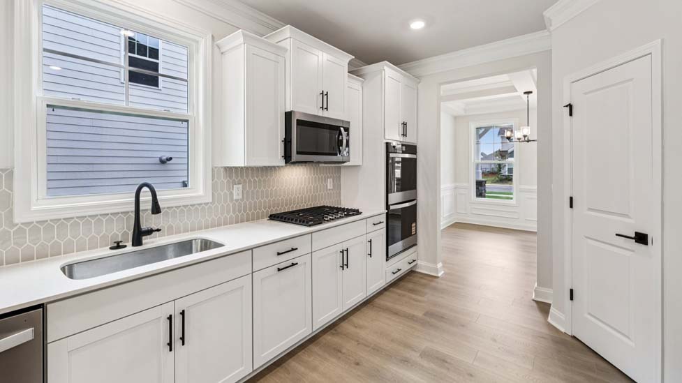Kitchen and island with white cabinets, breakfast area at island bar, and stainless steel appliances