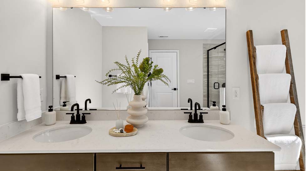 Primary bathroom with double sinks, brown cabinets and bathtub and glass door shower combination