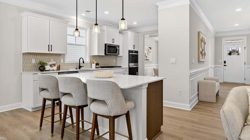 Kitchen and island with white cabinets, breakfast area at island bar, and stainless steel appliances