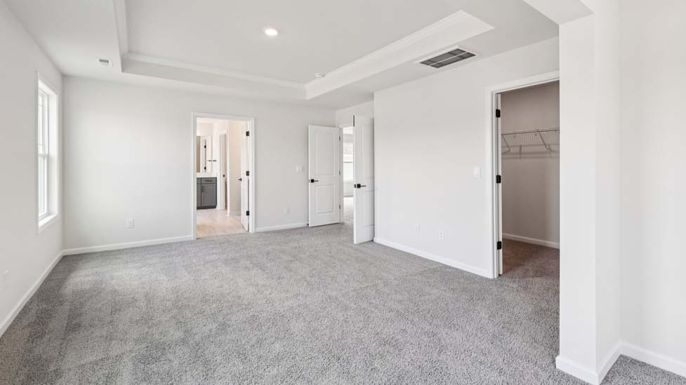 Primary carpeted bedroom with large windows