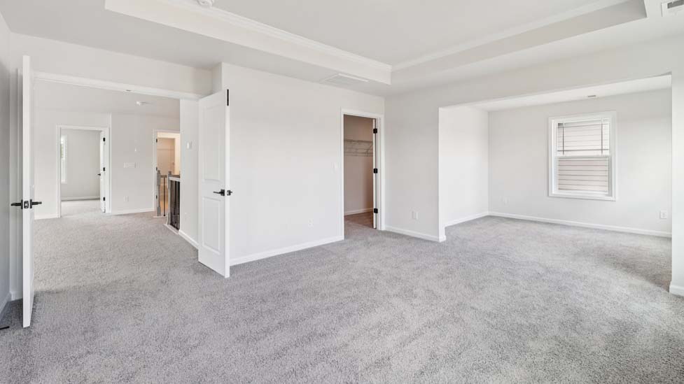 Primary carpeted bedroom with large windows