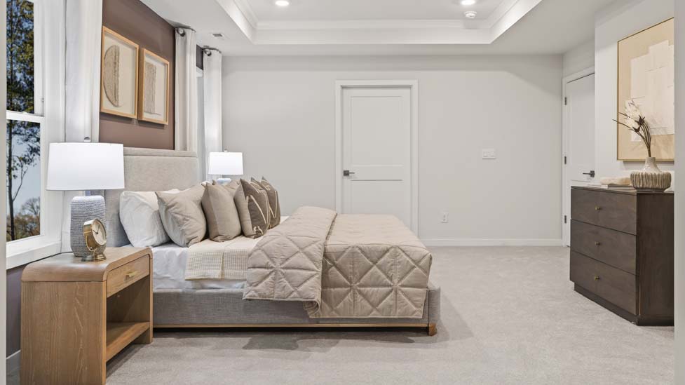 Primary carpeted bedroom with large windows