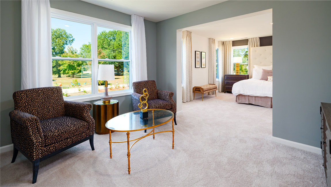 Carpeted sitting room in primary bedroom, with large window