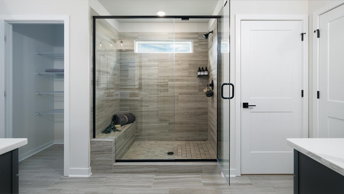 Primary bathroom with two sinks and counters, white cabinets, and wood floors