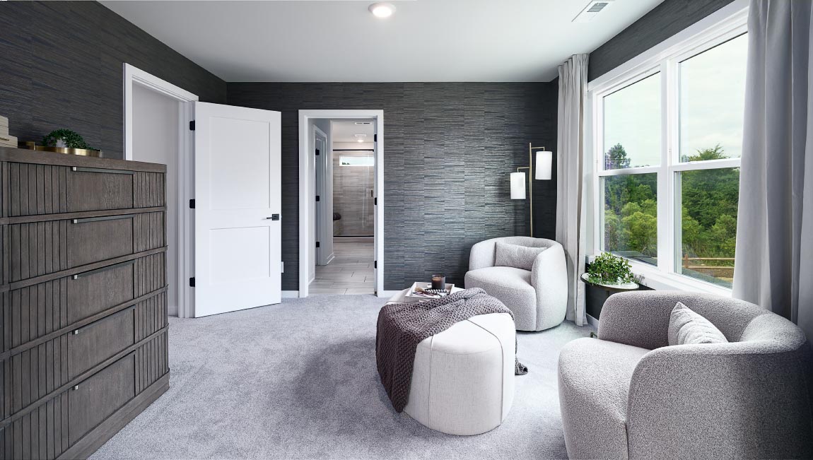 Carpeted sitting room in primary bedroom, with large window
