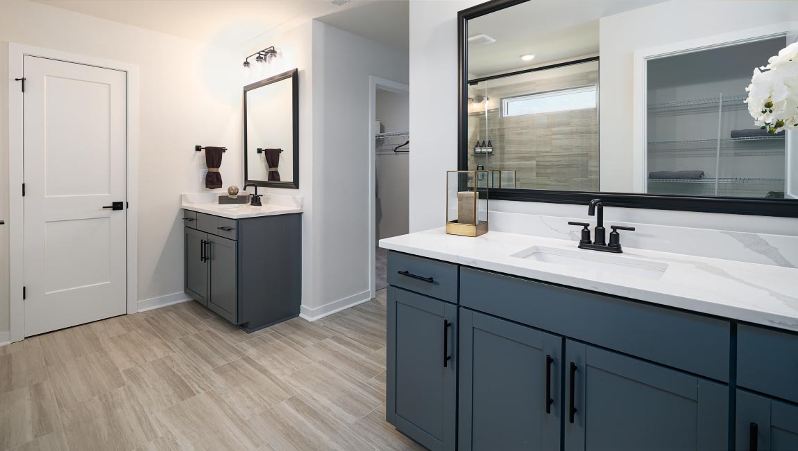Primary bathroom with two sinks and counters, white cabinets, and wood floors