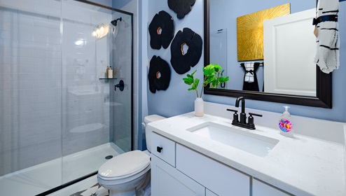 Bathroom with white counters, and cabinets and glass door shower
