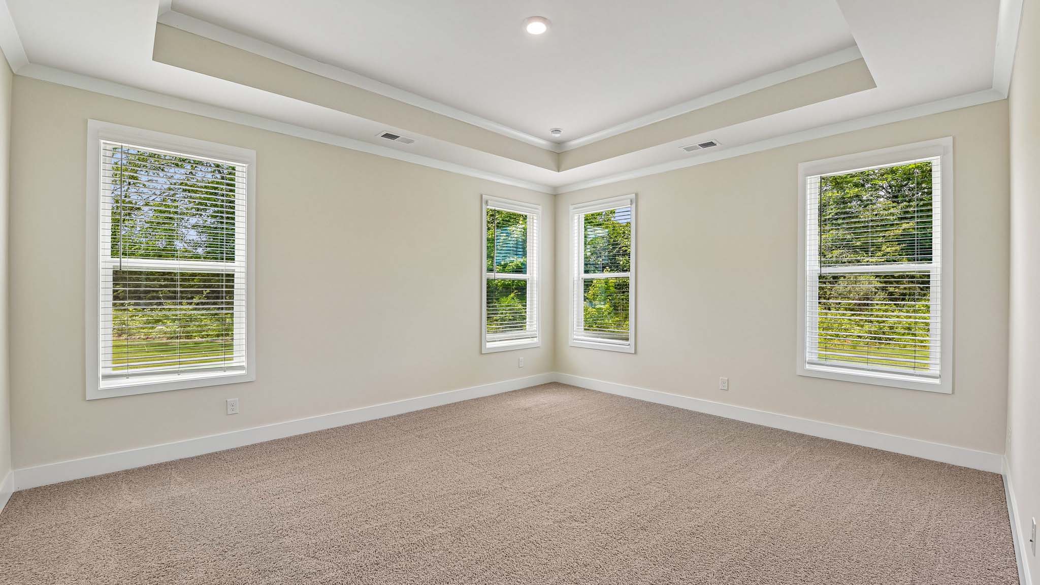 Carpeted primary bedroom with windows
