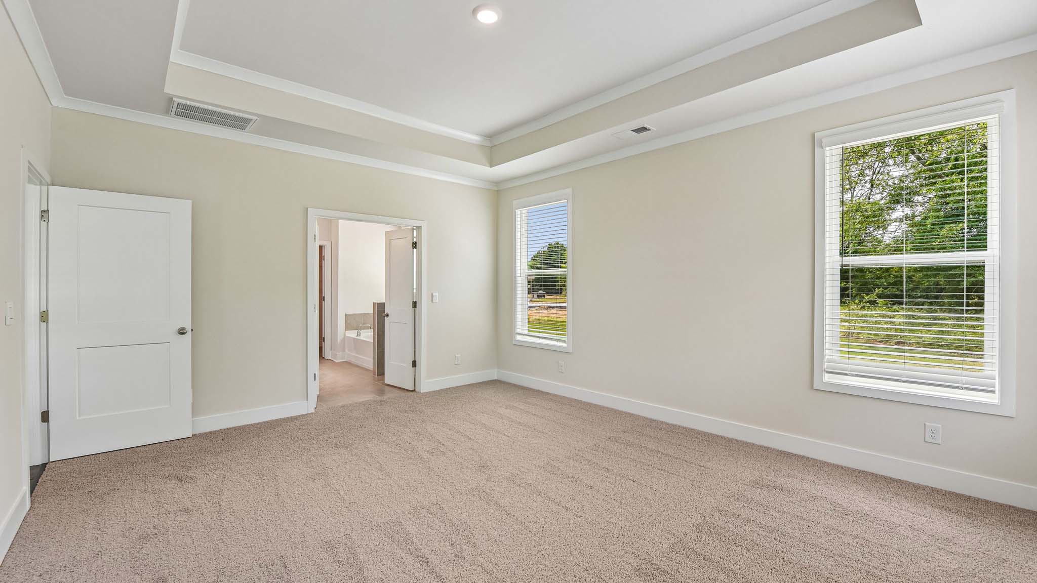 Carpeted primary bedroom with windows