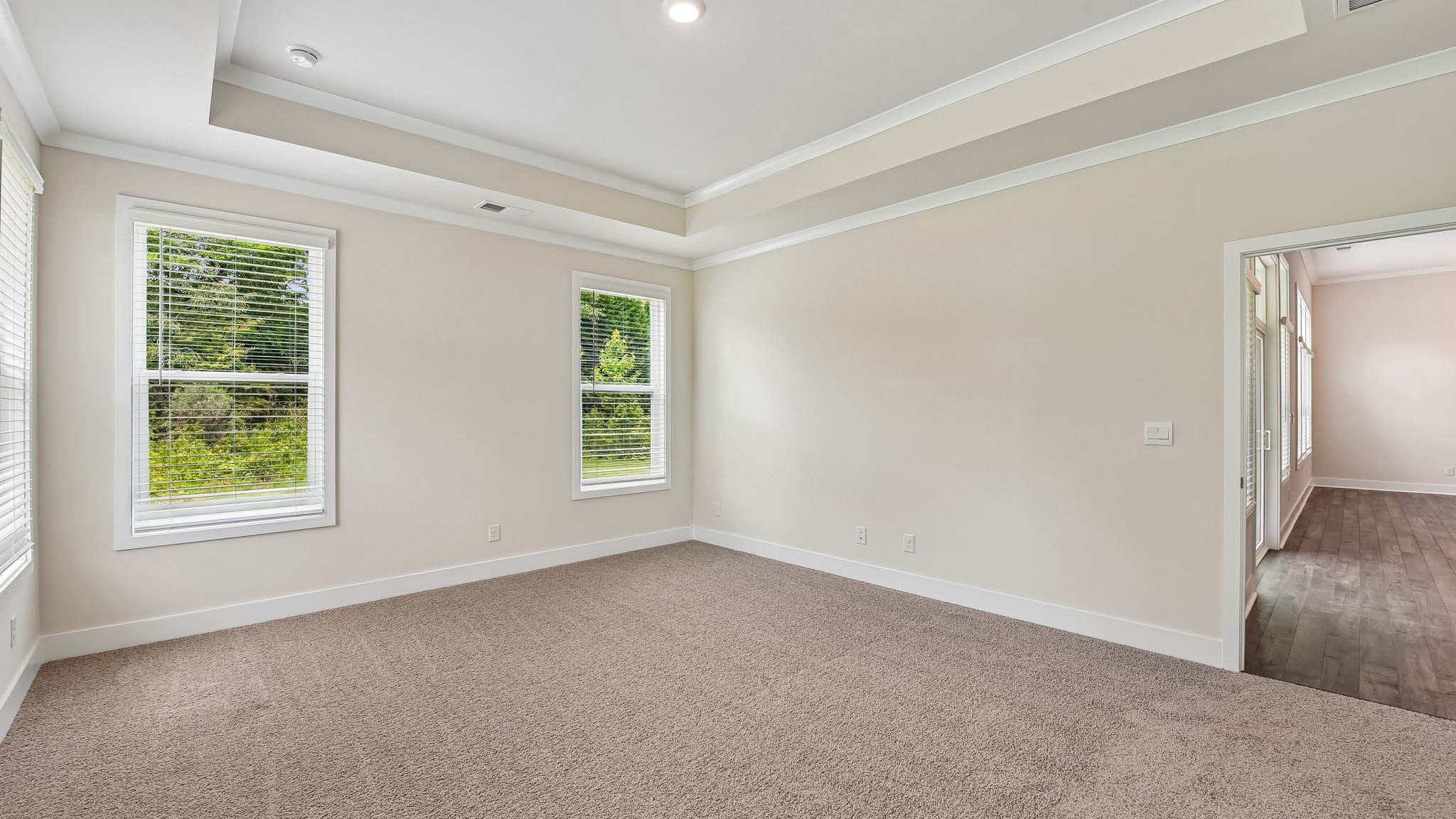 Carpeted primary bedroom with windows