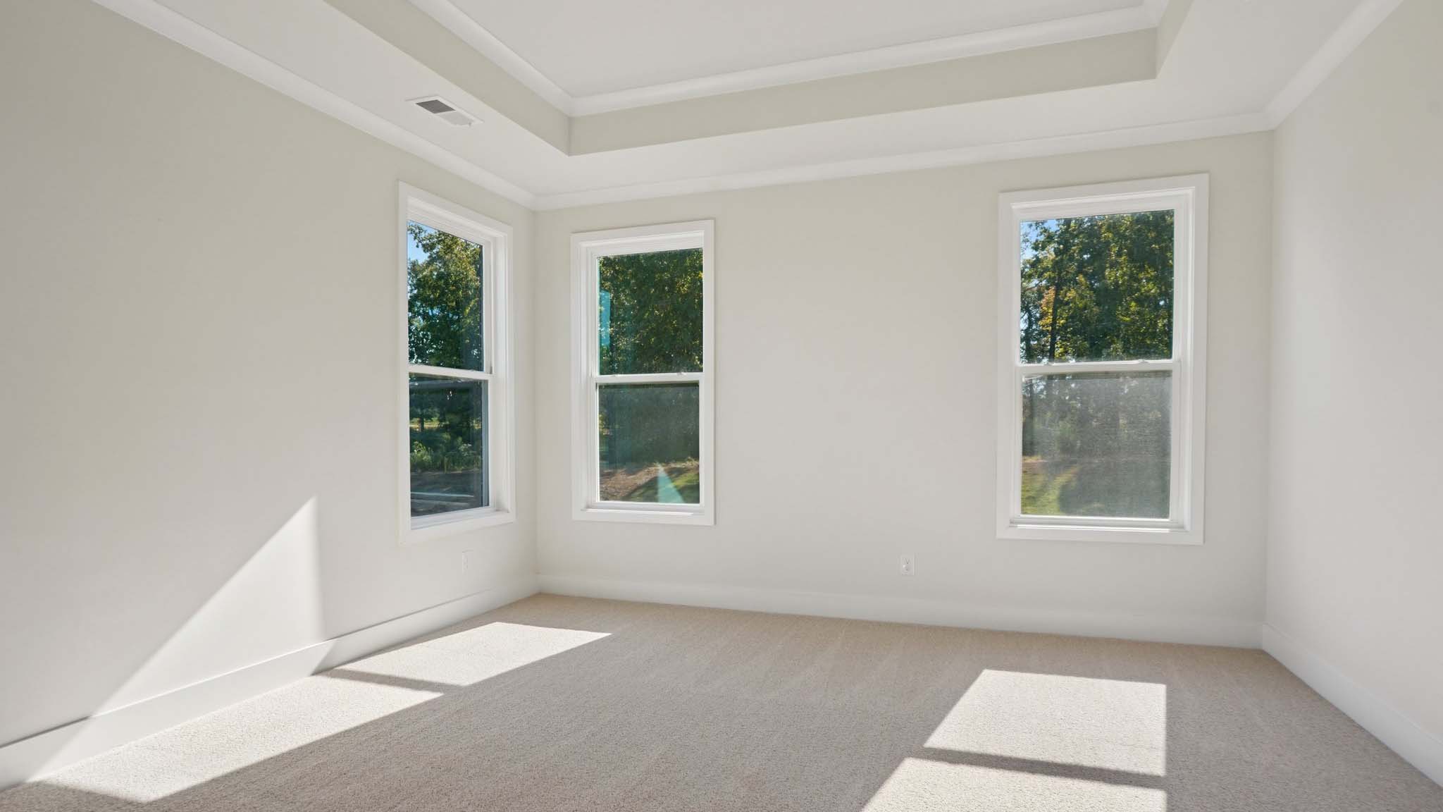 Carpeted primary bedroom with windows