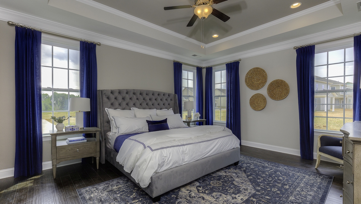 Primary bedroom with wood floors, and many large windows