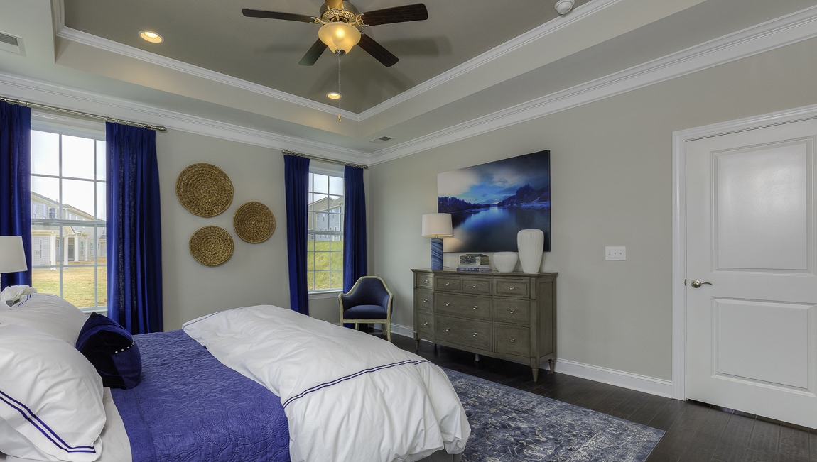 Primary bedroom with wood floors, and many large windows