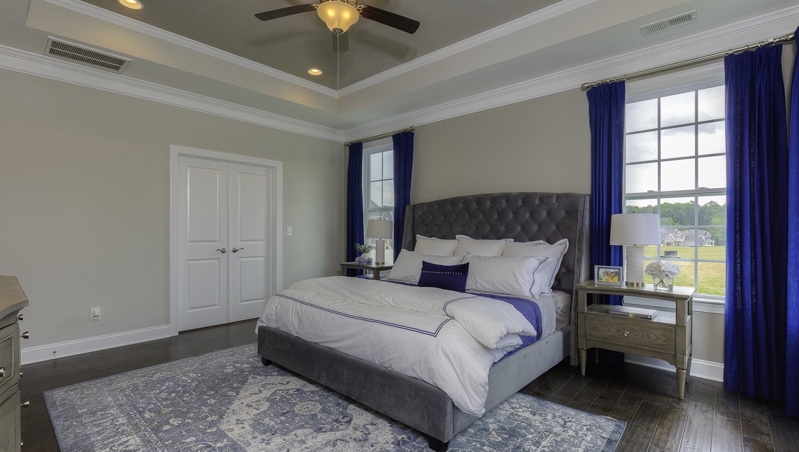 Primary bedroom with wood floors, and many large windows