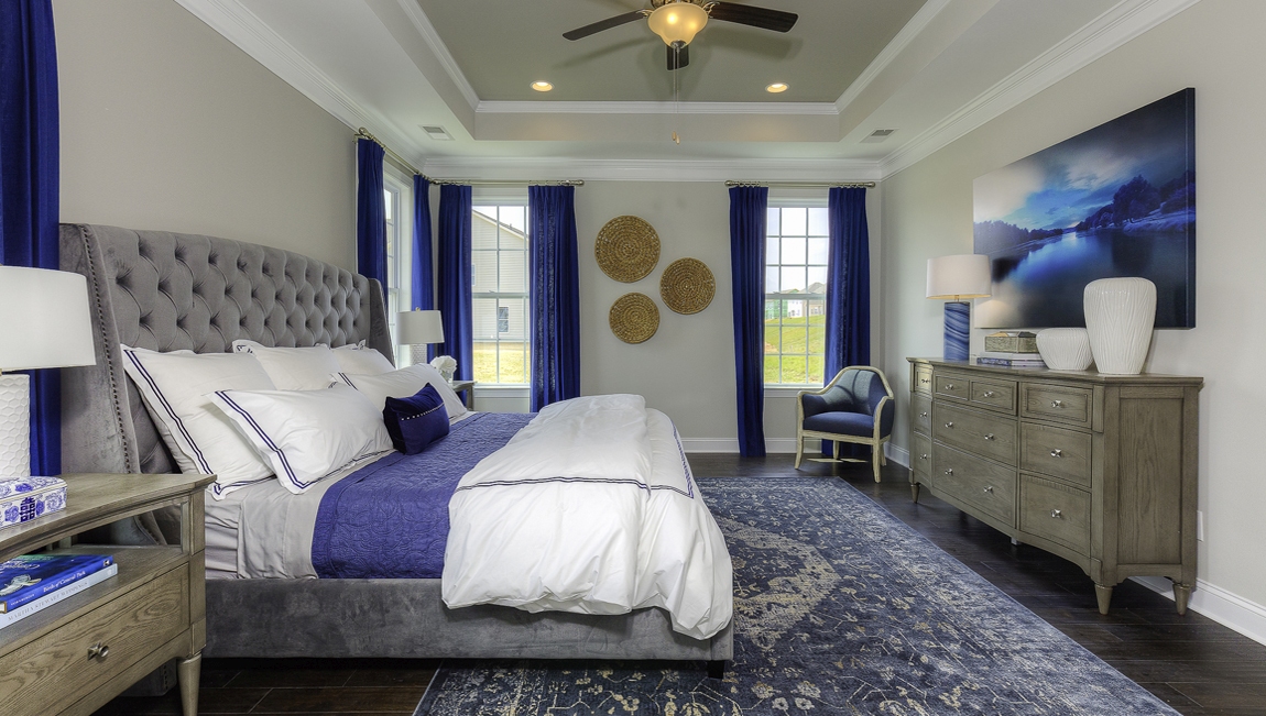 Primary bedroom with wood floors, and many large windows