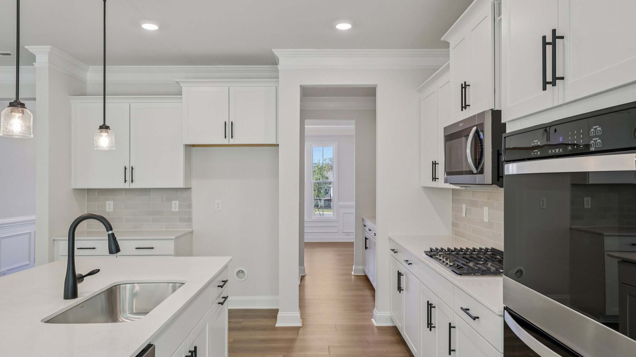 Kitchen and island with white countertops and white cabinets with stainless steel appliances