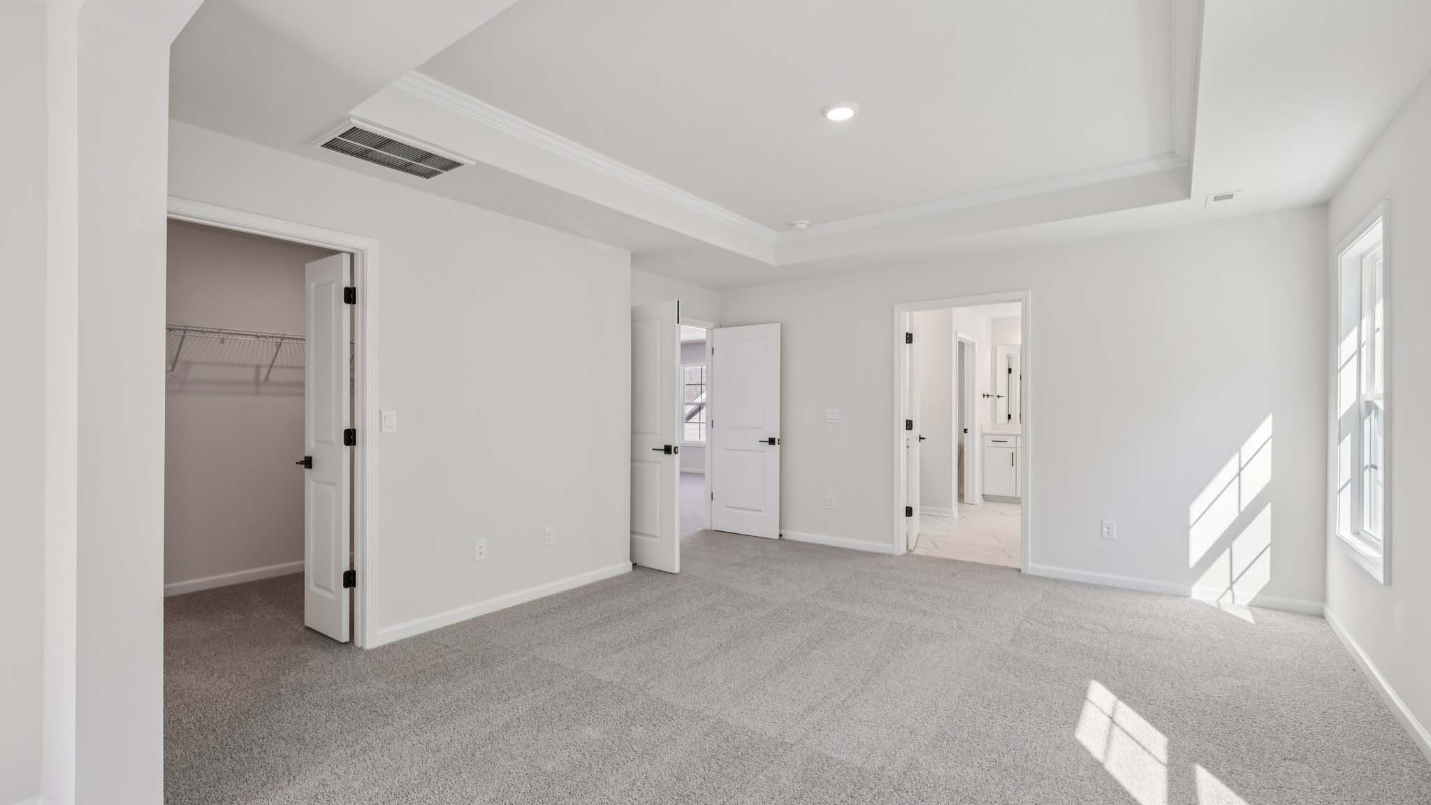 Primary carpeted bedroom with windows