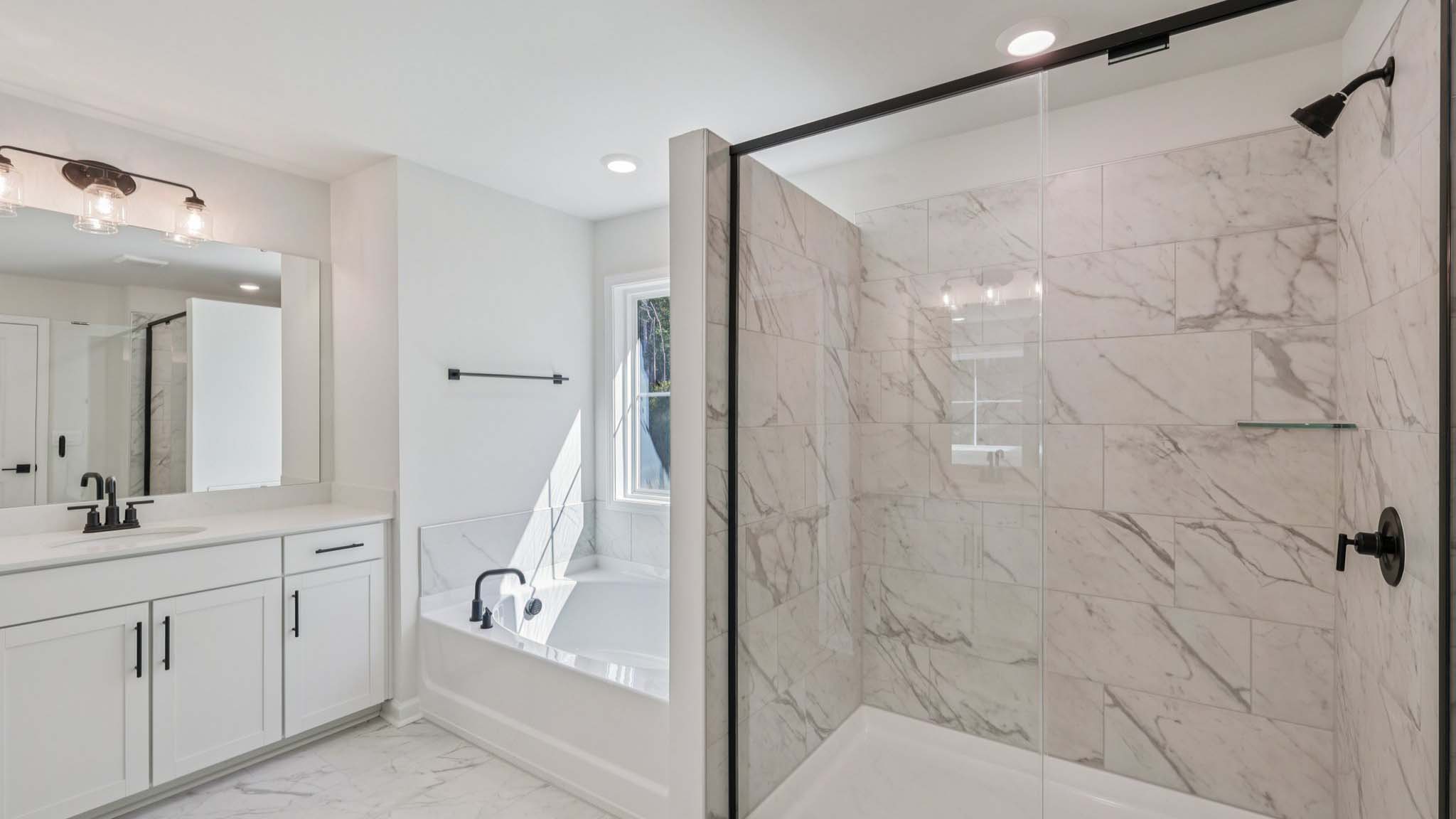 Primary bathroom with double sinks and standing glass shower with tub