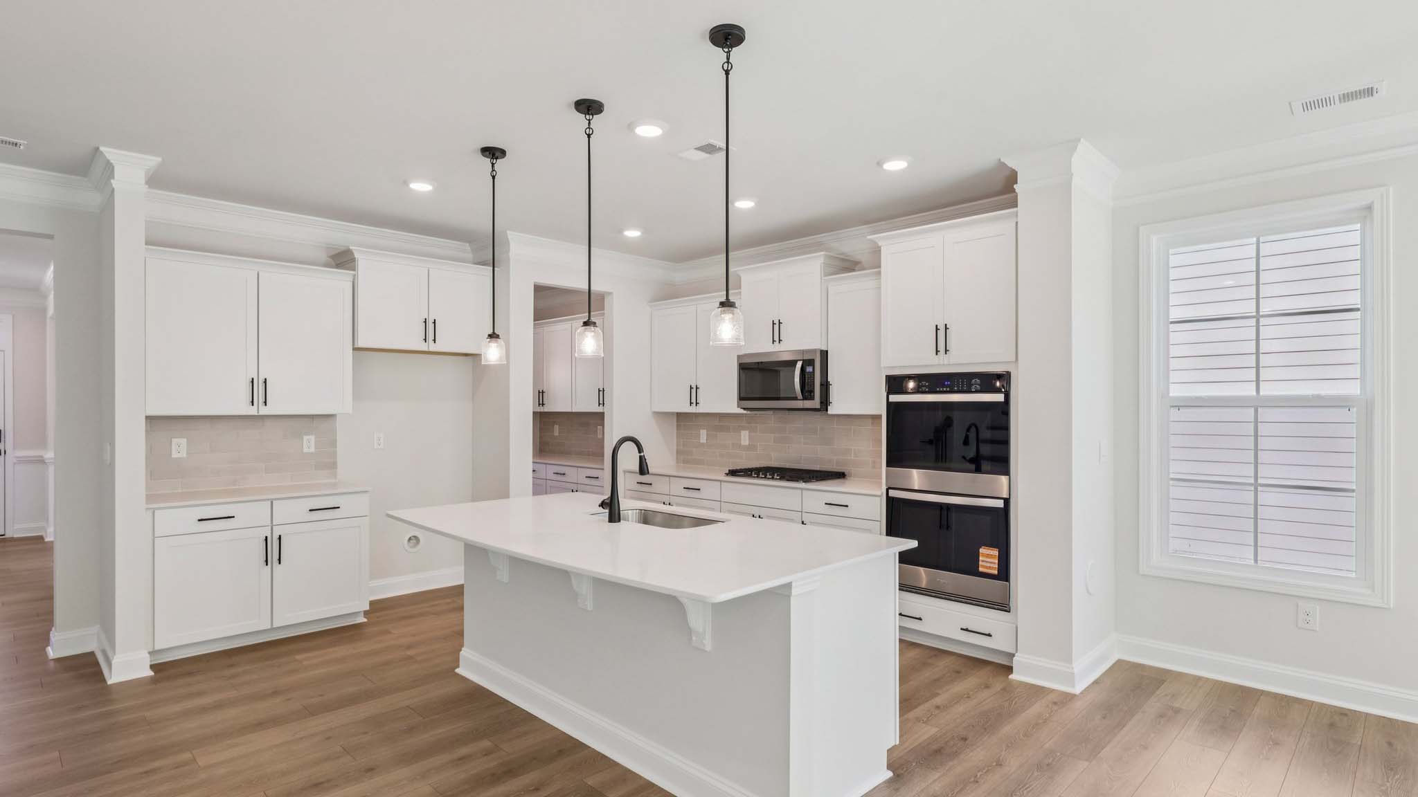 Kitchen and island with white countertops and white cabinets with stainless steel appliances