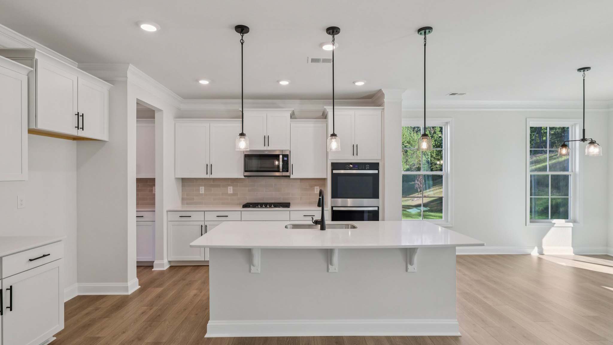 Kitchen and island with white countertops and white cabinets with stainless steel appliances