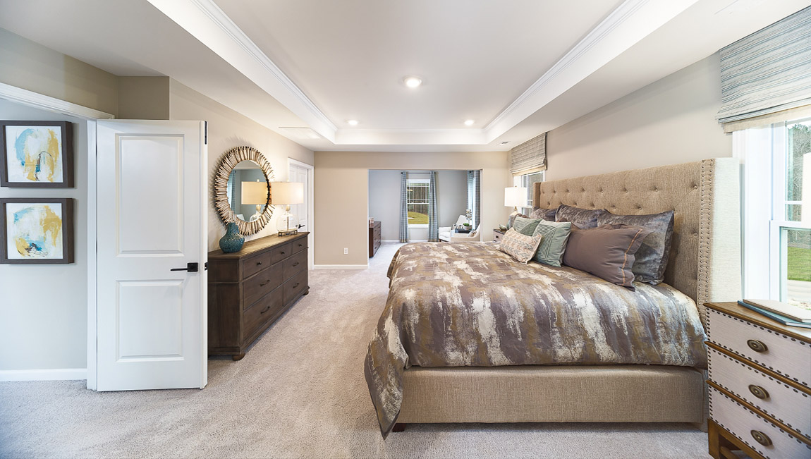 Primary carpeted bedroom with large windows