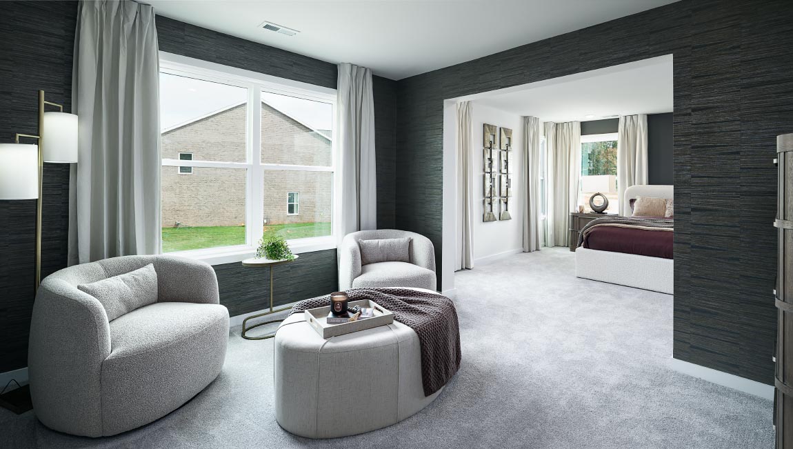 Carpeted sitting room in primary bedroom, with large window