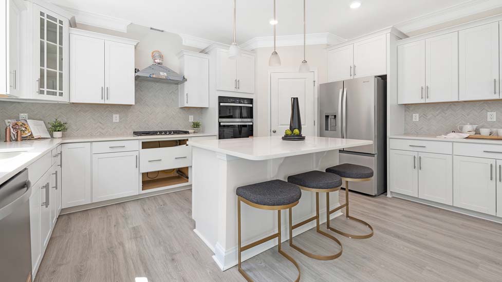 Kitchen and island with white cabinets, white rest of kitchen has brown cabinets