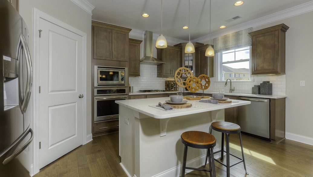 Kitchen and island with white cabinets, white rest of kitchen has brown cabinets