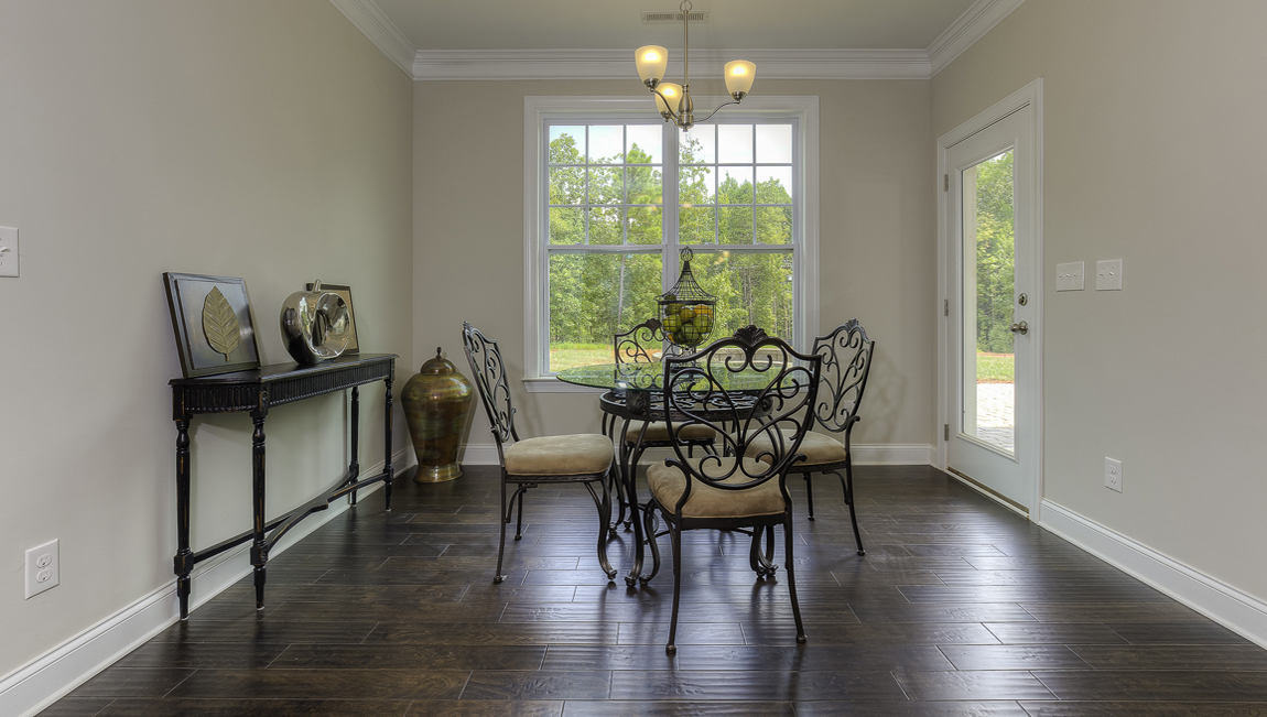 Breakfast area beside kitchen with wood floors, large window and back door