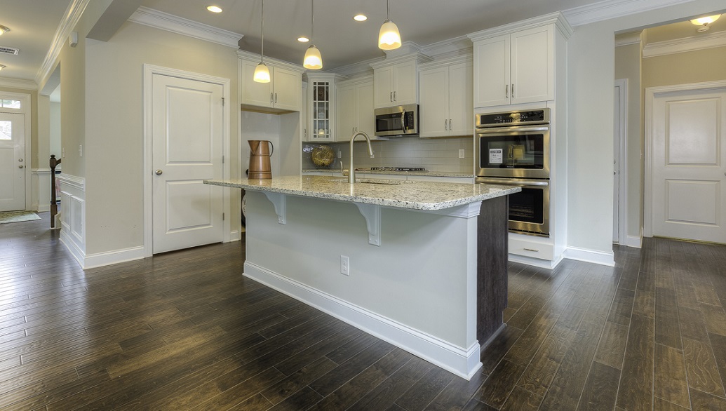 Kitchen and island with wood floors, white cabinets, and stainless steel appliances