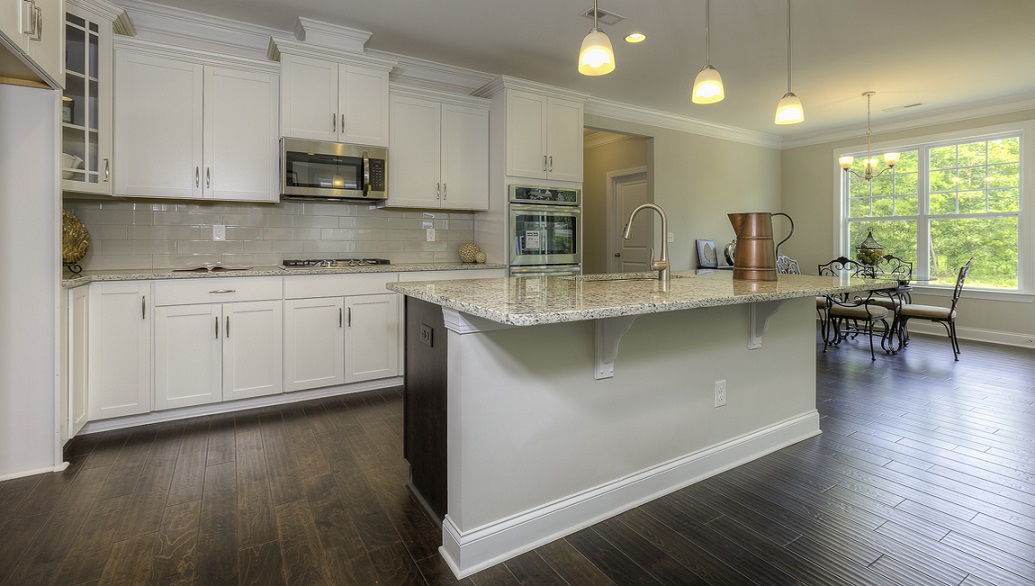 Kitchen and island with wood floors, white cabinets, and stainless steel appliances