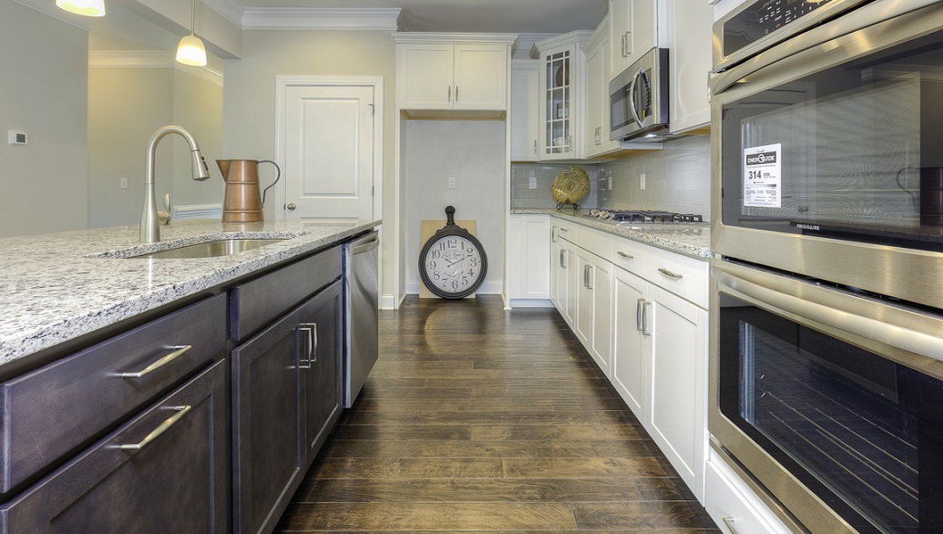 Kitchen and island with wood floors, white cabinets, and stainless steel appliances