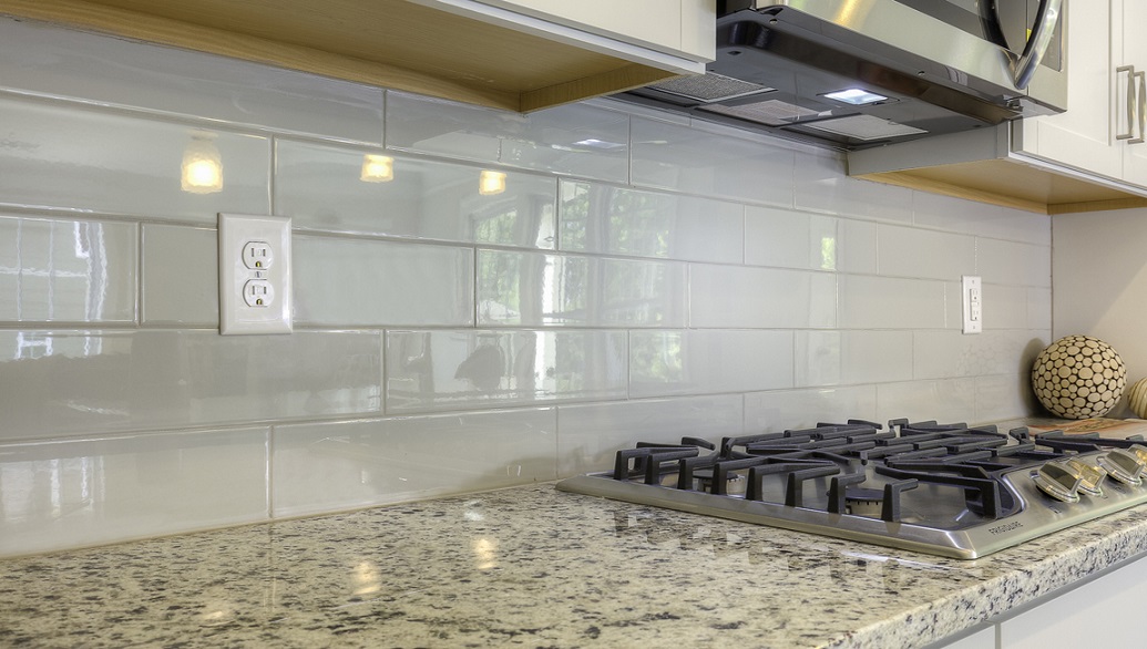 Kitchen and island with wood floors, white cabinets, and stainless steel appliances
