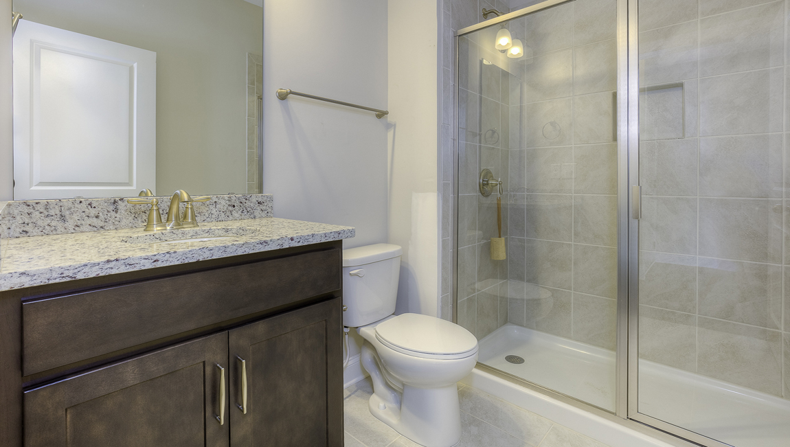 Bathroom with brown cabinets and glass door standing shower