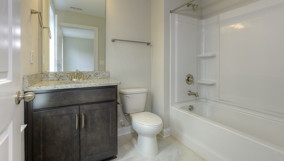 Bathroom with brown cabinets, double sinks, and bathtub