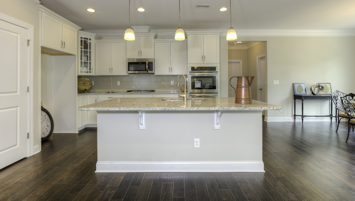 Kitchen and island with wood floors, white cabinets, and stainless steel appliances