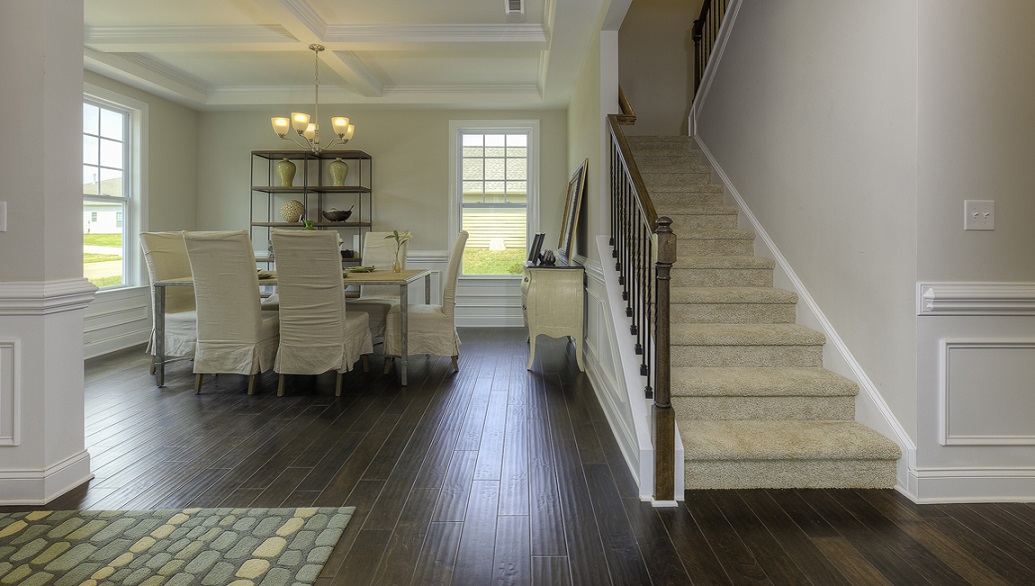 Welcoming foyer with wood floors, and view of staircase, front door and dining room