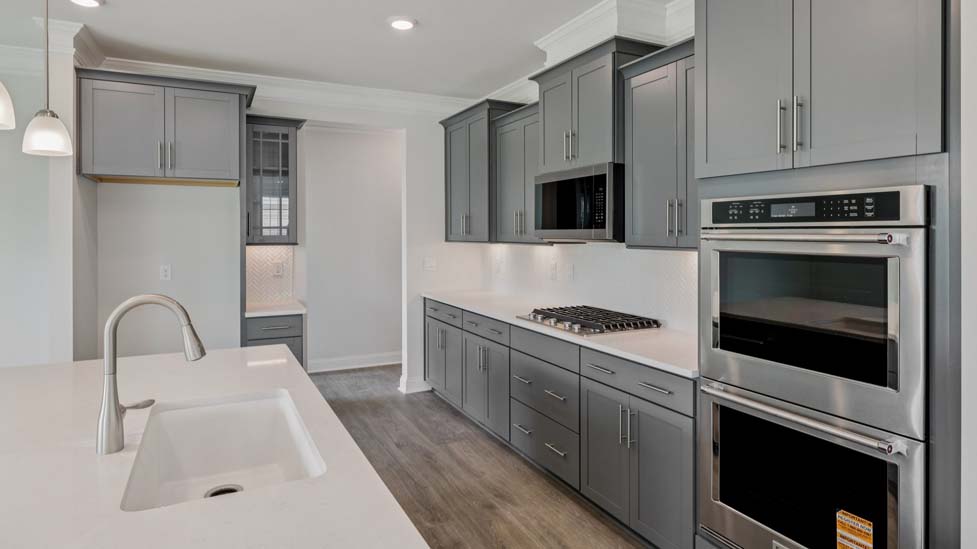 Kitchen and island with wood floors, white cabinets, and stainless steel appliances