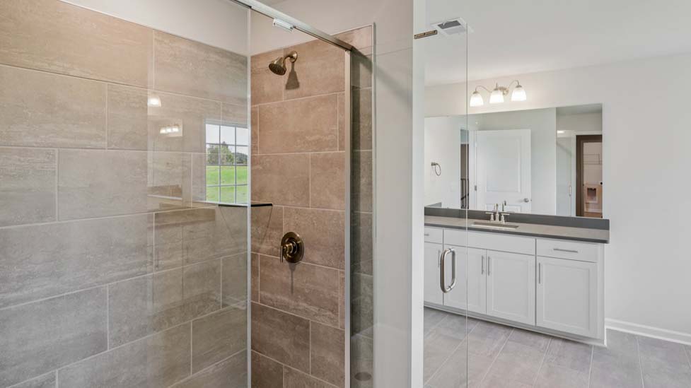 Primary bathroom with white cabinets, double sinks, and separate bathtub and standing glass door shower