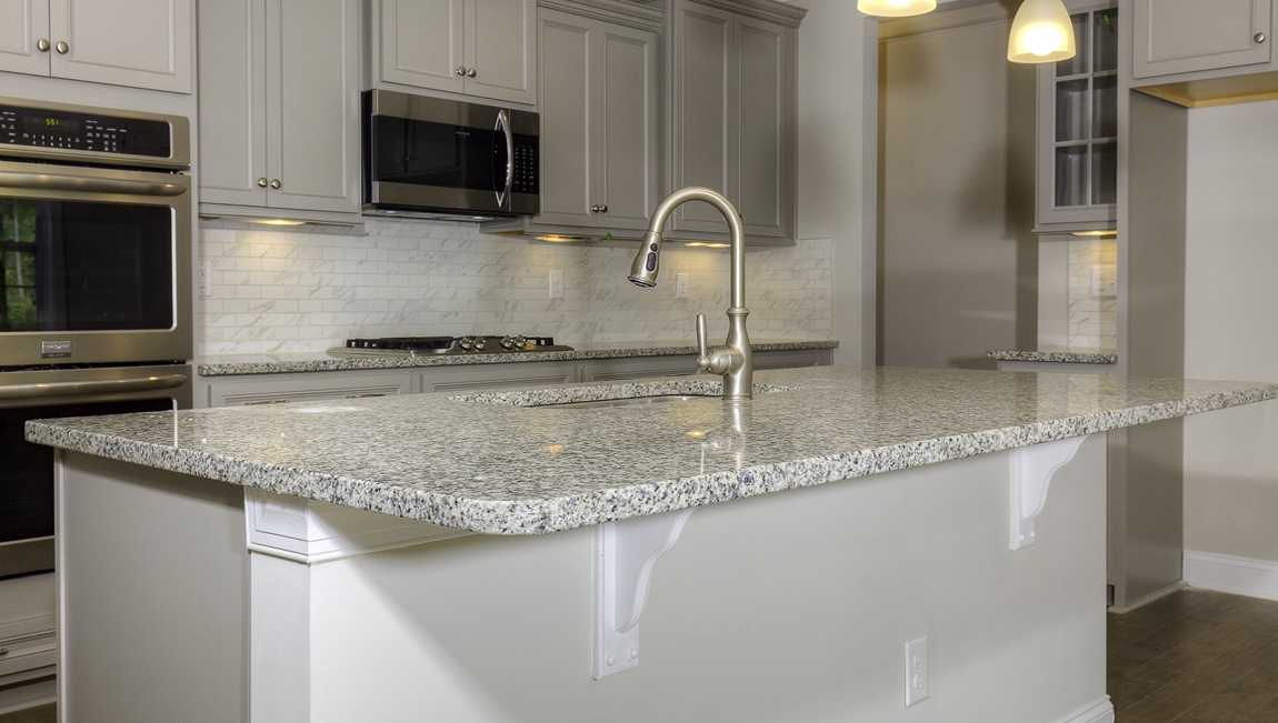 Kitchen and island with wood floors, white cabinets, and stainless steel appliances