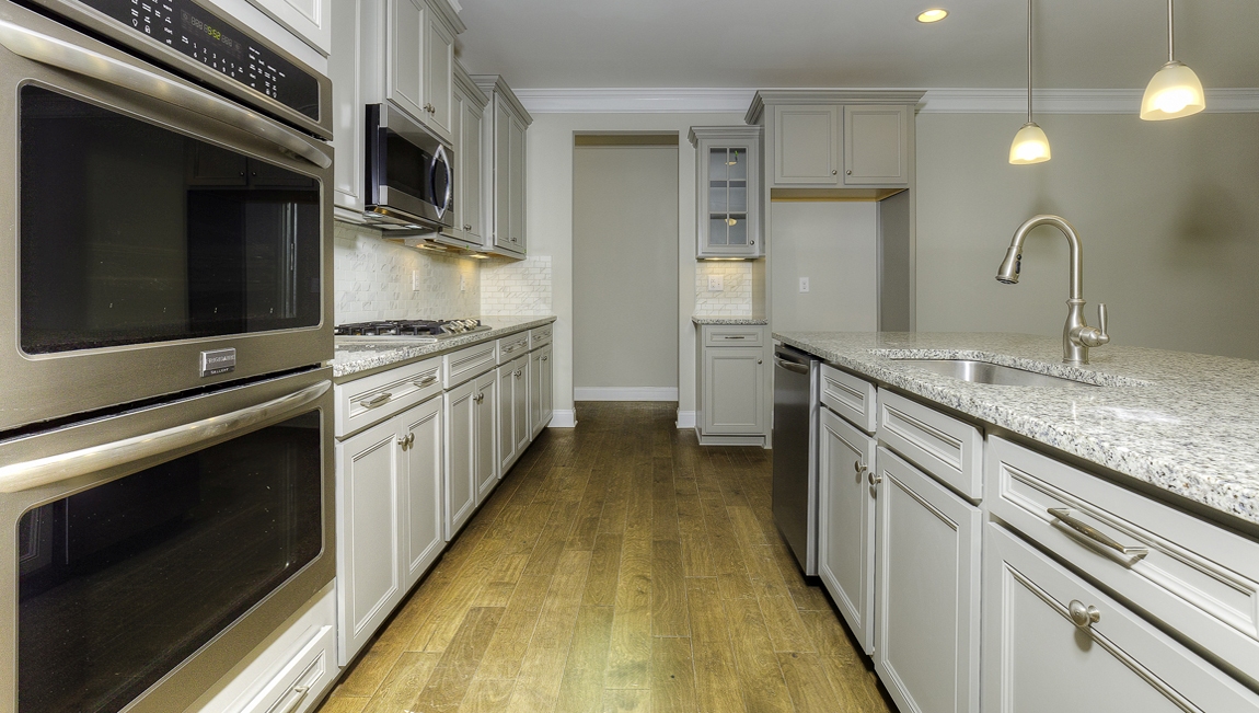 Kitchen and island with wood floors, white cabinets, and stainless steel appliances