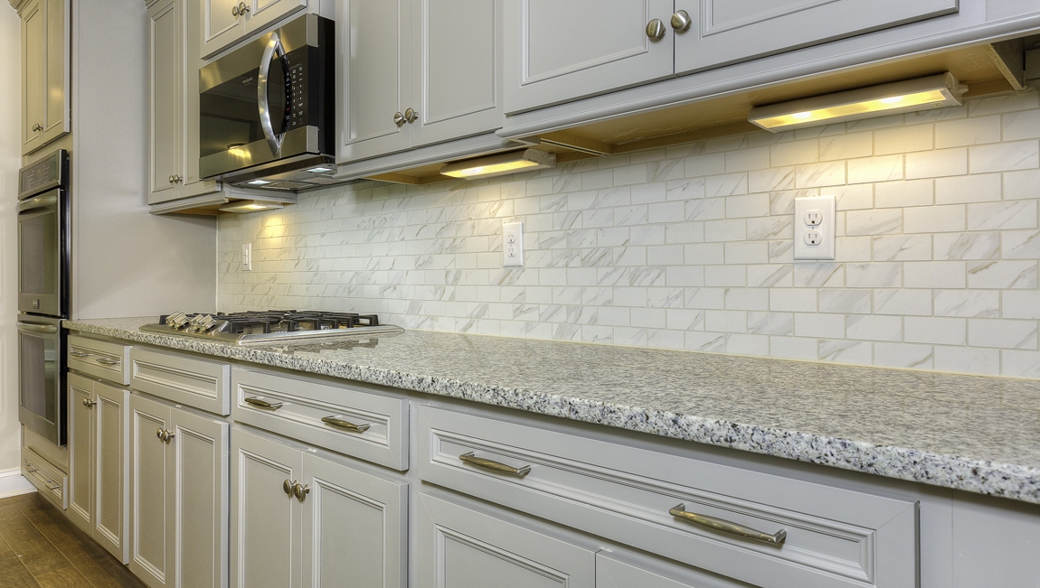 Kitchen and island with wood floors, white cabinets, and stainless steel appliances